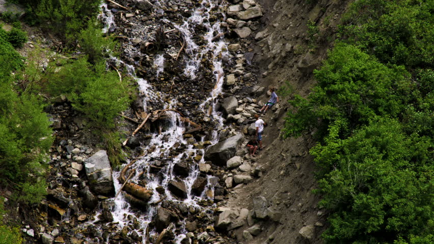 Three youth climbing up the rocks near the stream that flows from Bridal Veil
