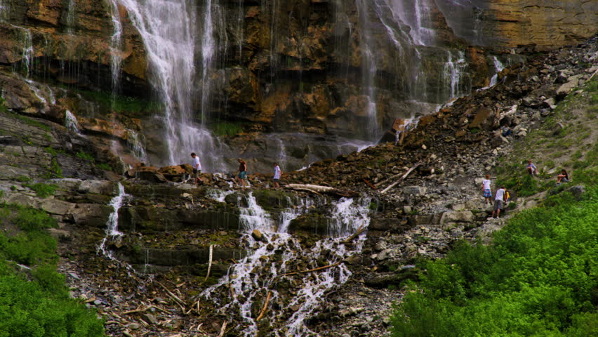 People climbing around the rocks at the base of Bridal Veil Falls in Provo