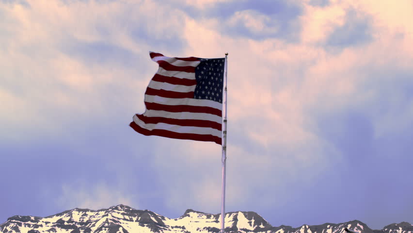 United States flag waving in the breeze at dusk.  The snowy top of the Wasatch
