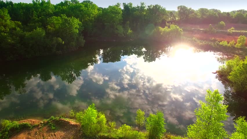 Amazing natural beauty, aerial flyover of tiny pond reflecting sky.
