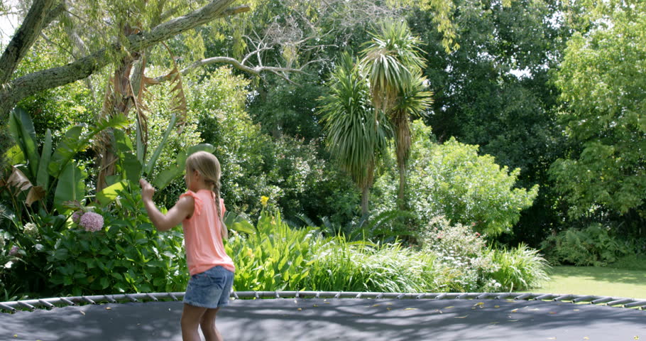 Blonde girl jumping on trampoline in the garden