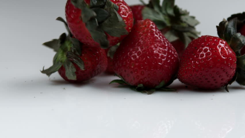 A bunch of strawberries with a single one rolling off.