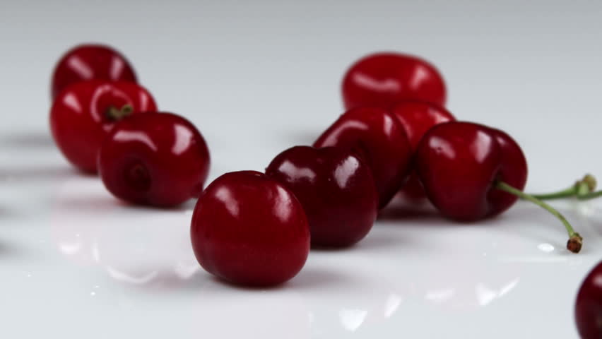 Red cherries falling onto table.