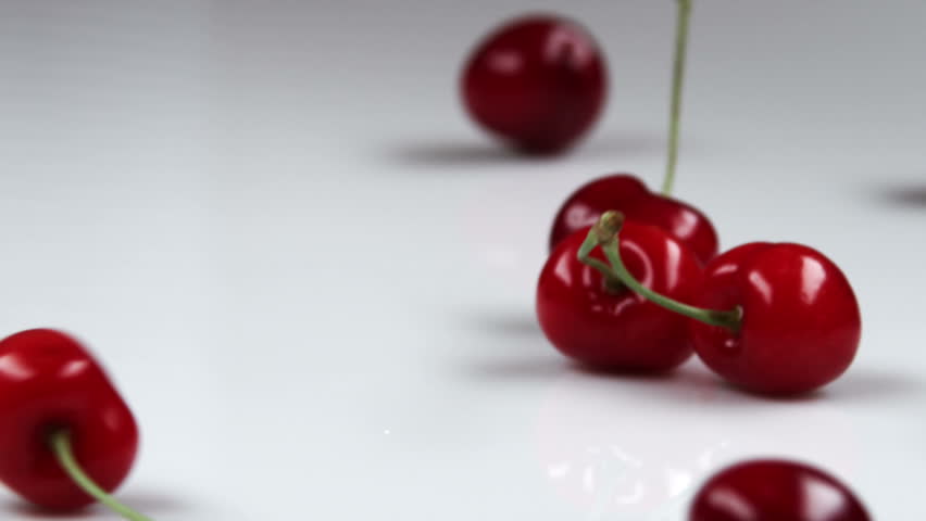 Red cherries falling onto table.