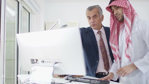 4K Smiling Arab businessmen working together on computer. Shot on RED Epic. UK - April, 2016