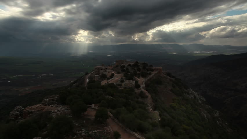Time lapse shot of sun rays piercing through dark clouds to Nimrod Fortress and
