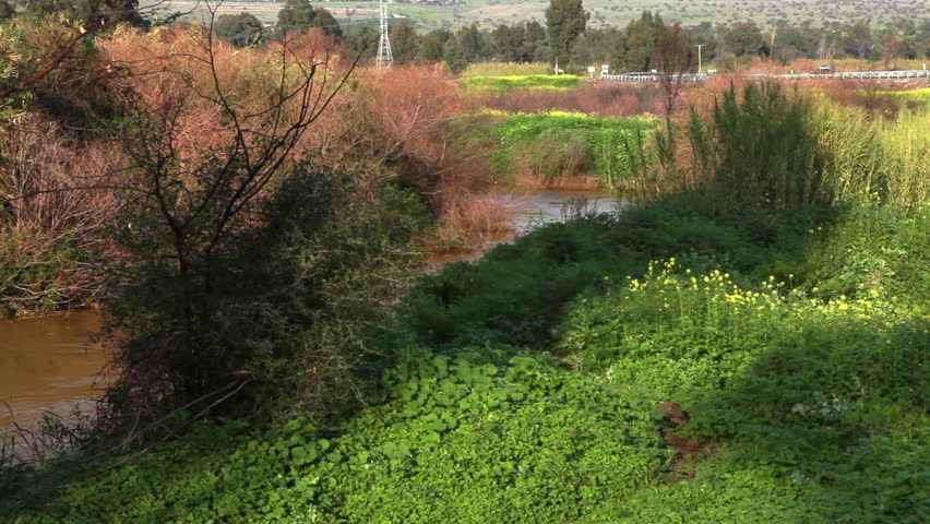 A bend in the flow of the reddish brown River Jordan in the Galilee of Israel.  