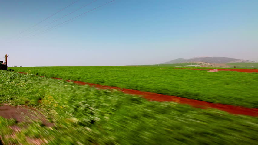 Drive-by in the Ein Harod farmland region of Israel showing a lush green field. 