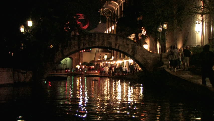 San Antonio Texas Riverwalk. Tourists at restaurants and shops. Vacation area. Tourists eating at outside tables with bright lights and festive atmosphere.  During Final Four basketball tournament.