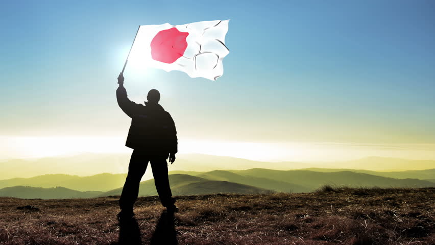 Successful silhouette man winner waving Japan flag on top of the mountain peak, 4k cinemagraph