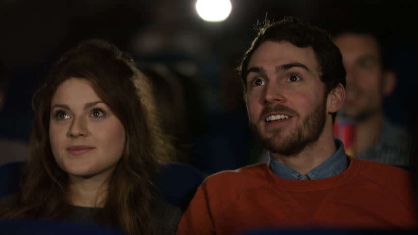 4K Cinema audience watching a movie with focus on happy young dating couple. Shot on RED Epic. UK - April, 2016