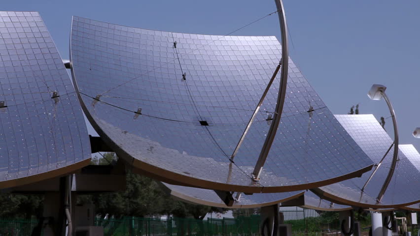 Pan left to right along a row of solar panels with the blue sky of Israel in the