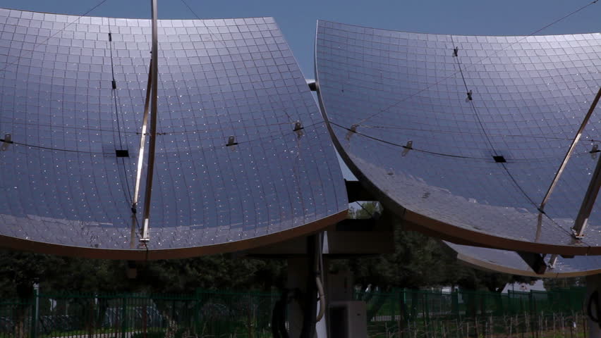 Pan left to right along a row of solar panels with the blue sky of Israel in the