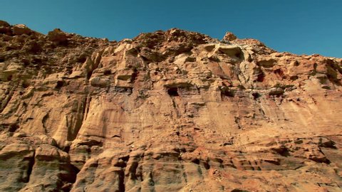 Medium wide, close-up drive-by of the desert cliff face from the bottom of the Mitzpe Ramon Crater in Israel.