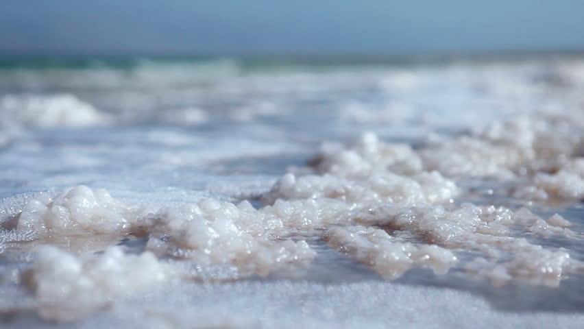 Low angle of the water lapping over the salt deposits on the shore of the Dead