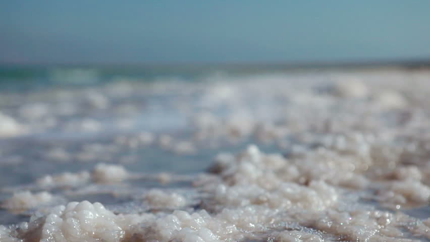 Low angle of the water lapping over the salt deposits on the shore of the Dead