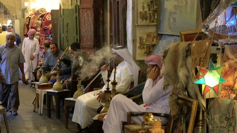 Doha, Qatar - February 2016: Men smoking Sheesha or water pipes in cafe at Souq Waqif, Doha, Qatar