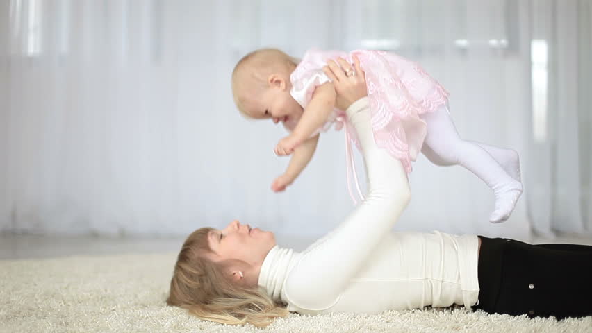 Mother playing with baby girl on the floor
