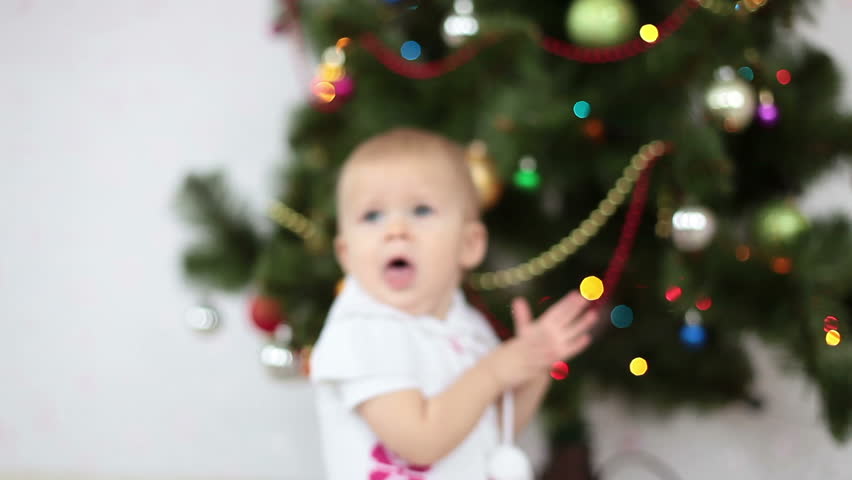 Baby girl yawns beside the Christmas Tree