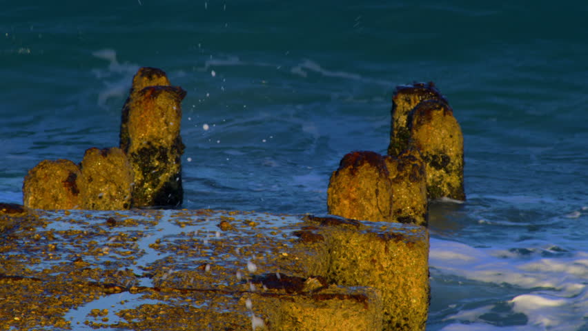 Close-up shot of a ruin pier as the Mediterranean waves crash over the remaining pylons  in Tel Aviv, Israel. 