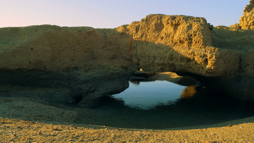 This is a very slow pan of a rock arch over a Mediterranean coastal pool at Dor