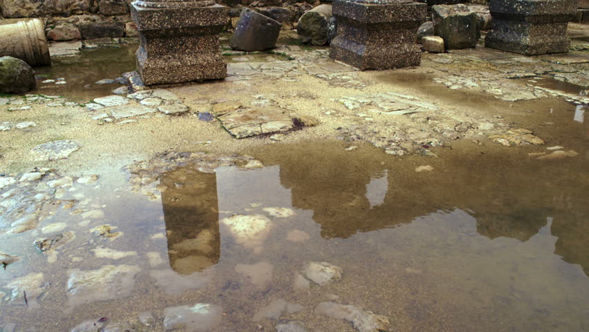 A tilt from a pool of water reflecting the walls of the ruined synagogue up to