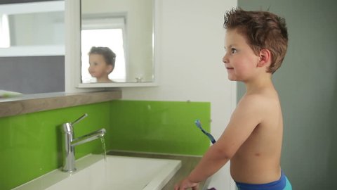 Boy brushing his teeth in the mirror