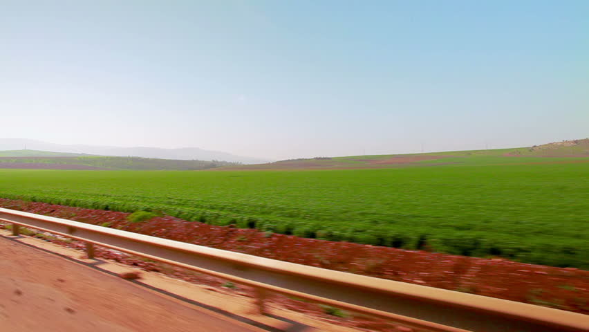 Drive-by in the Ein Harod farmland region of Israel with a lush green field of