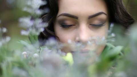 Close up face of young beautiful woman posing to camera surrounded by spring flowers