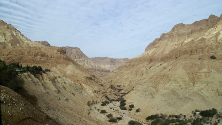 Dry river bed through a desert mountain valley in Israel.  Striated clouds in