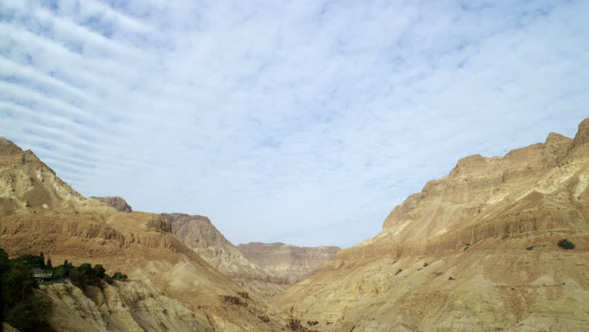 Tilt down to a dry river bed through a desert mountain valley in Israel. 
