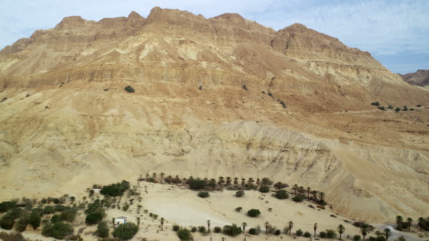 Pan left from a barren mountain to a dry river bed through a desert mountain