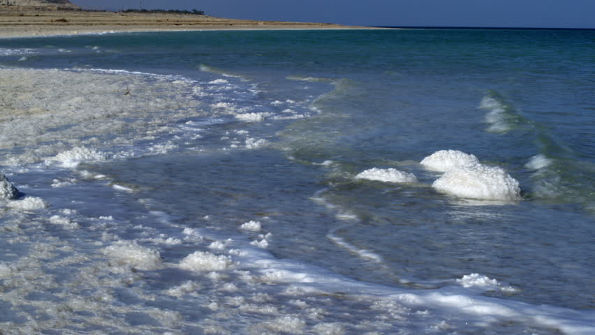 Salty shoreline of the Dead Sea in Israel,  Waves coming in splashing over salt