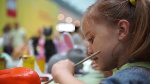 Little girl paints ceramic cat at the table