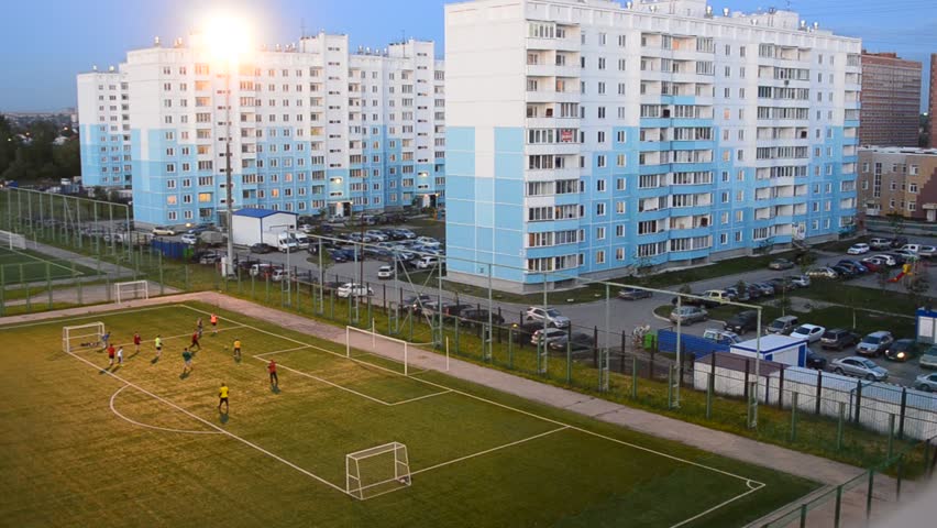 Unidentified men playing football in the evening on the football field among cities in Novosibirsk.