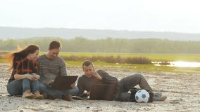 Three men with laptops on the sand slow motion video