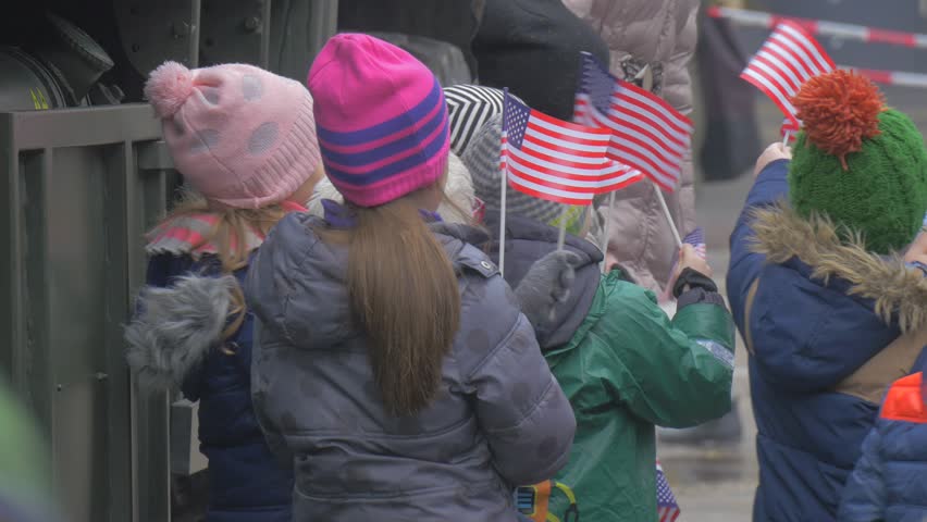 Kids Waving a Paper us Flags Excursion Military Camp Nato Forses at the City Square, Soldier in Uniform, Military Vehicles, Smiling Children Are Looking at Military Vehicles and Equipment, Standing