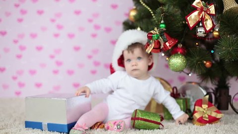 Baby girl prepares the gifts near the Christmas tree