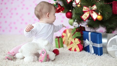 Newborn near a Christmas tree sitting on the floor 