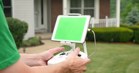 A man uses a RC controller for a drone or UAV outside a house. Green screen generic tablet with optional corner markers for advanced screen tracking.	 	 Video de stock