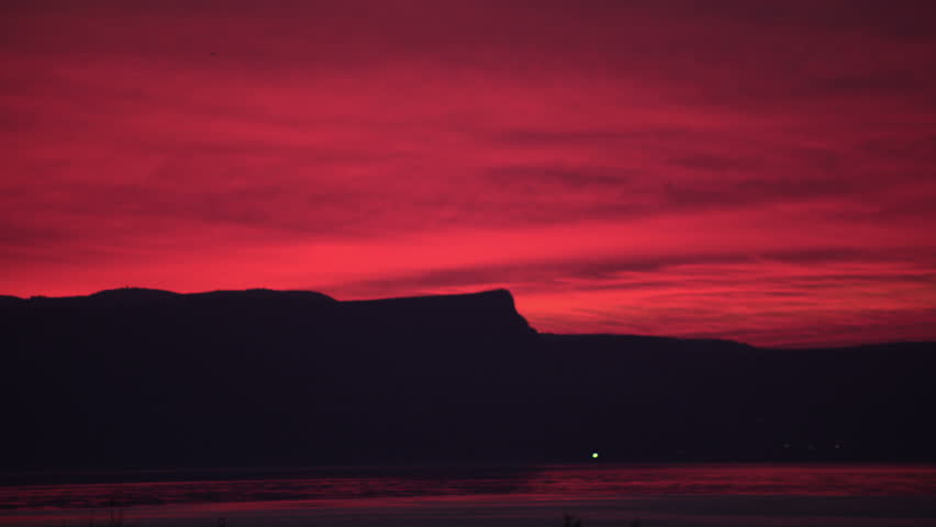 Fire red sunset sky and reflecting off the Sea of Galilee in Israel.  A single