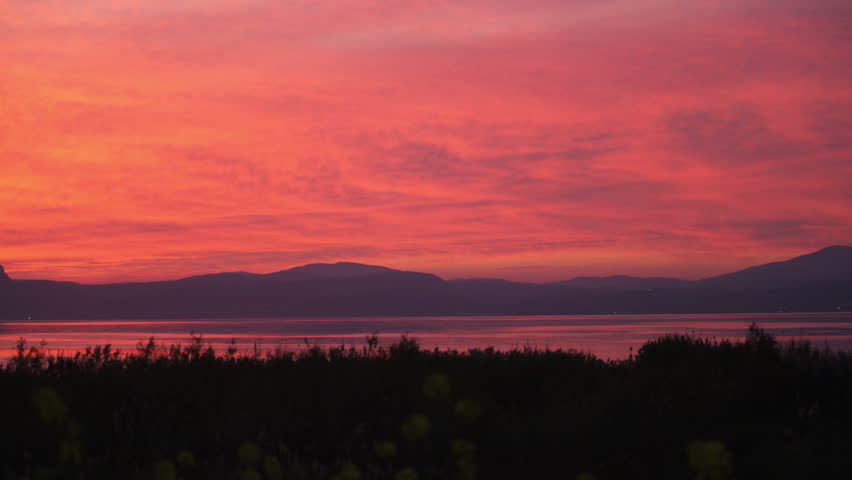 Fire red sunset sky and reflecting off the Sea of Galilee in Israel.  The most