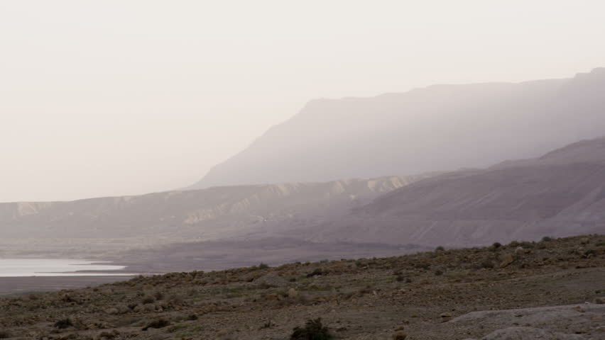 Pan of a wide shot from the Ein Gedi mountains of Israel, to the Dead Sea.  Hazy