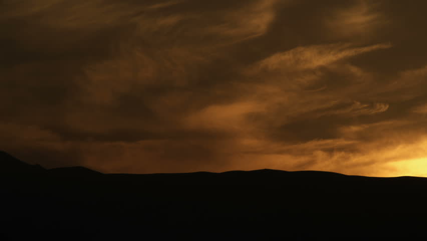 Pan left to right of silhouetted Ein Gedi mountains in Israel, with golden lit