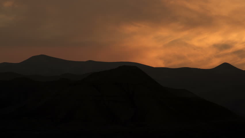 Pan left to right if silhouetted Ein Gedi mountains with black and golden lit