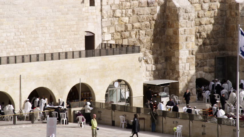 Wide panning shot of male Jews praying at the Western Wall (Wailing Wall) at a
