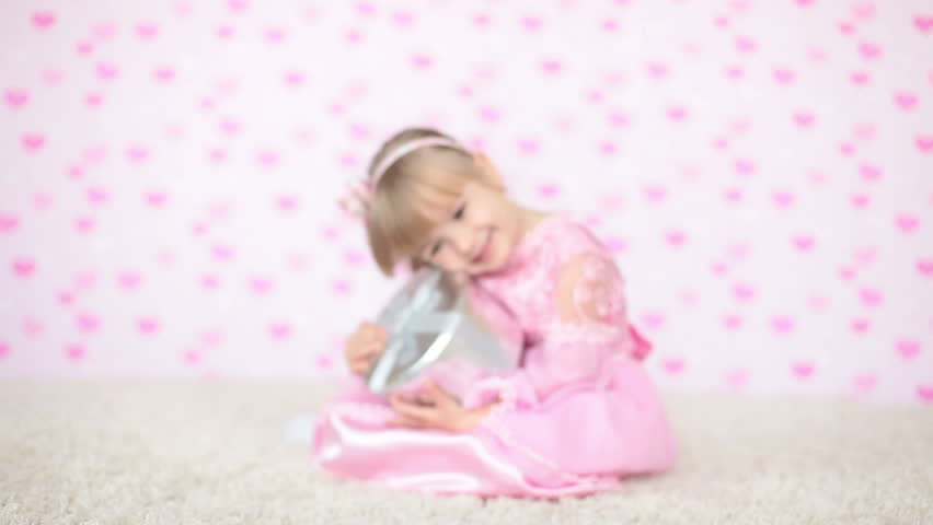 Girl holding a gift sitting on the carpet 