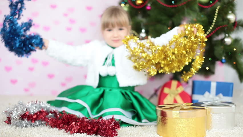 Laughing girl plays with Christmas decorations 