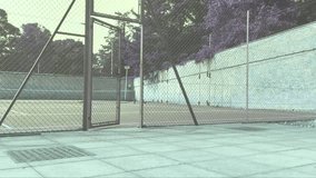 An establishing shot of an outdoor tennis court, in muted cool tones