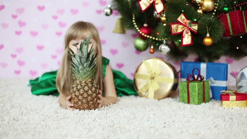 Child looks out over the pineapple lying on the floor near the Christmas Tree
